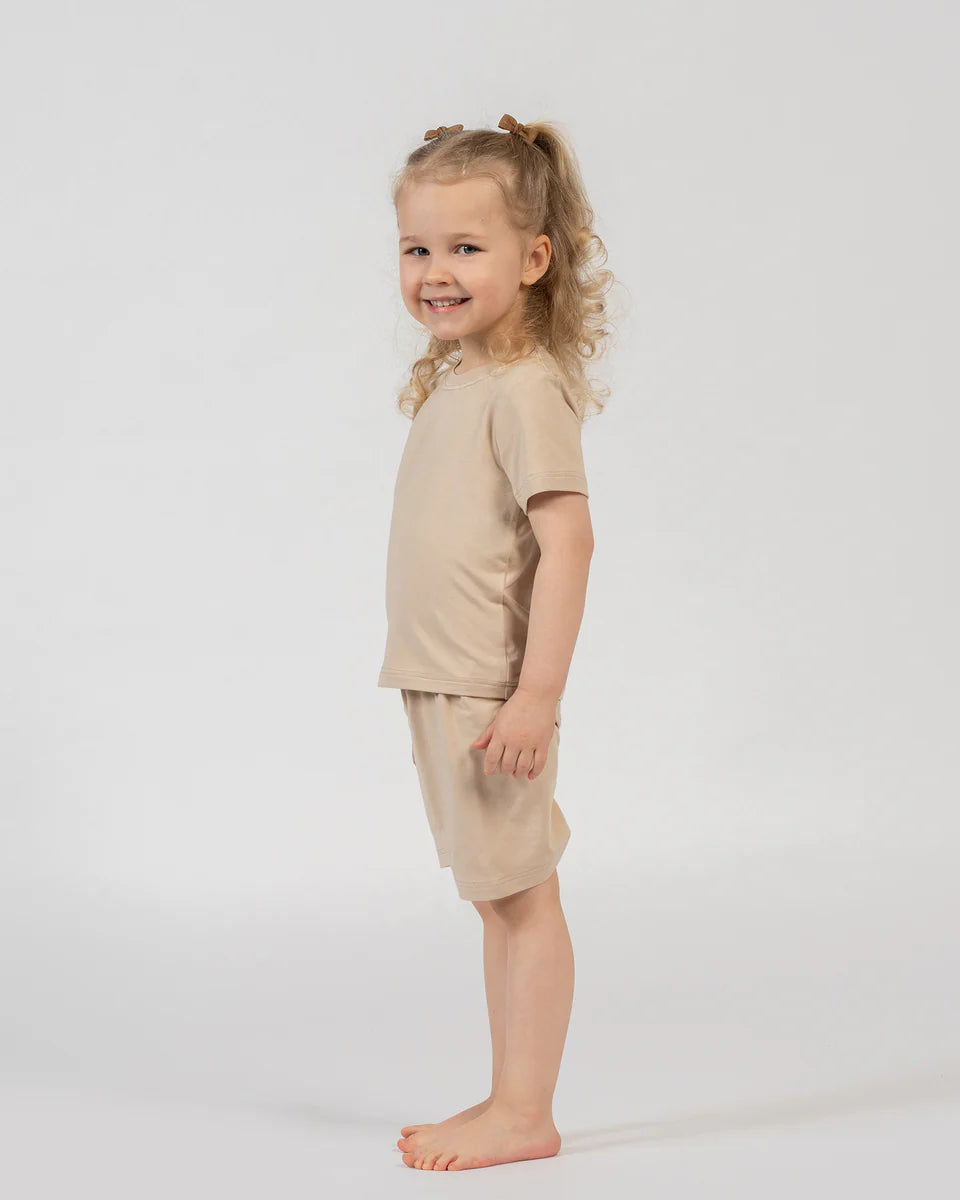 Young girl wearing a beige outfit on a white background