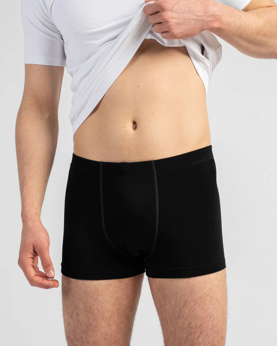 Person wearing black boxer briefs with a plain background