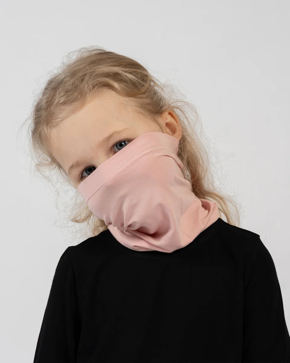 Child wearing a pink neck gaiter on a plain background