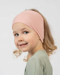 Child wearing a pink headband against a white background