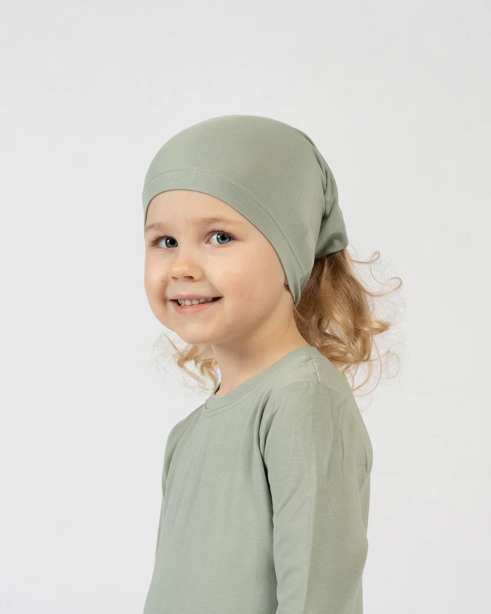 Child wearing a green headscarf and shirt against a white background