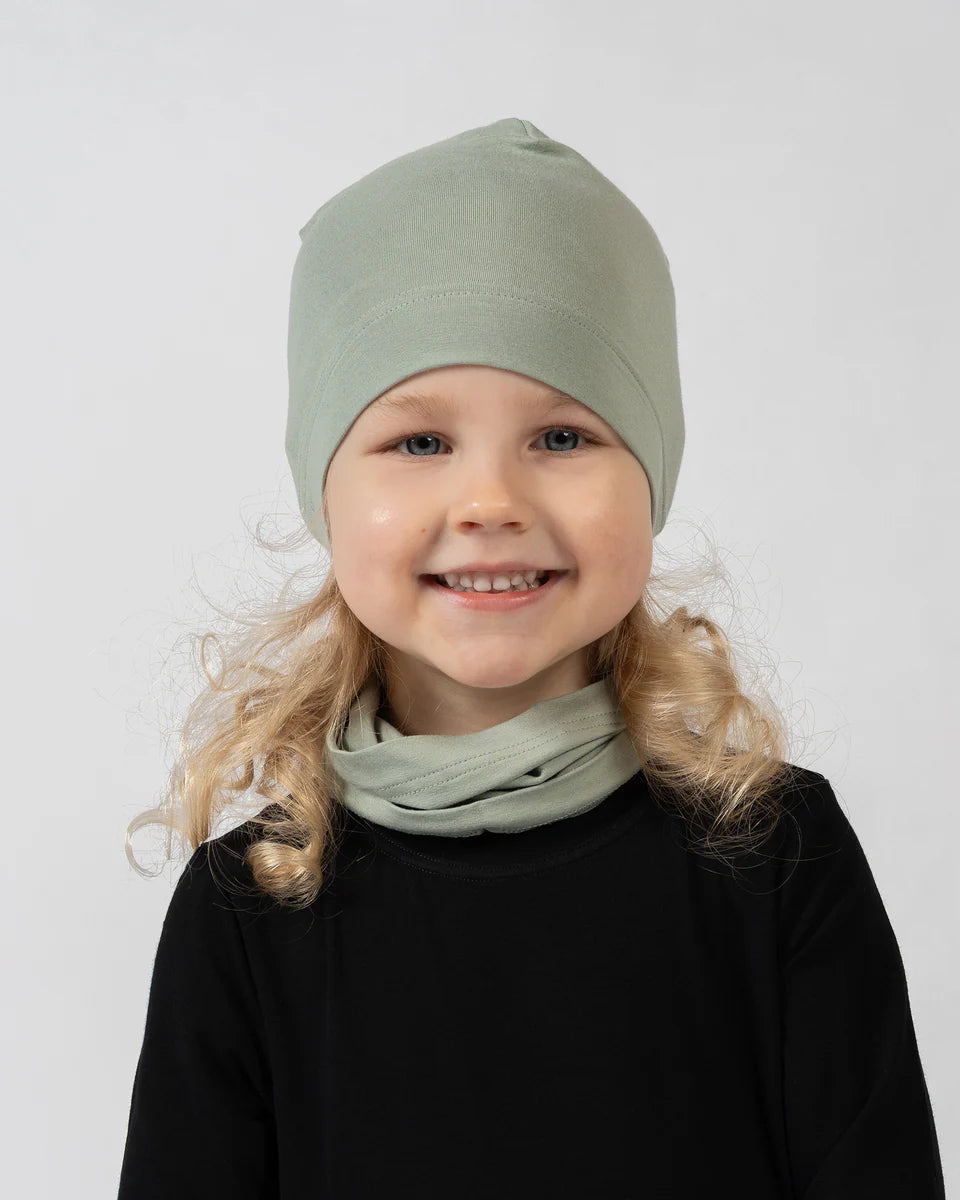 Child wearing a green beanie and scarf on a white background