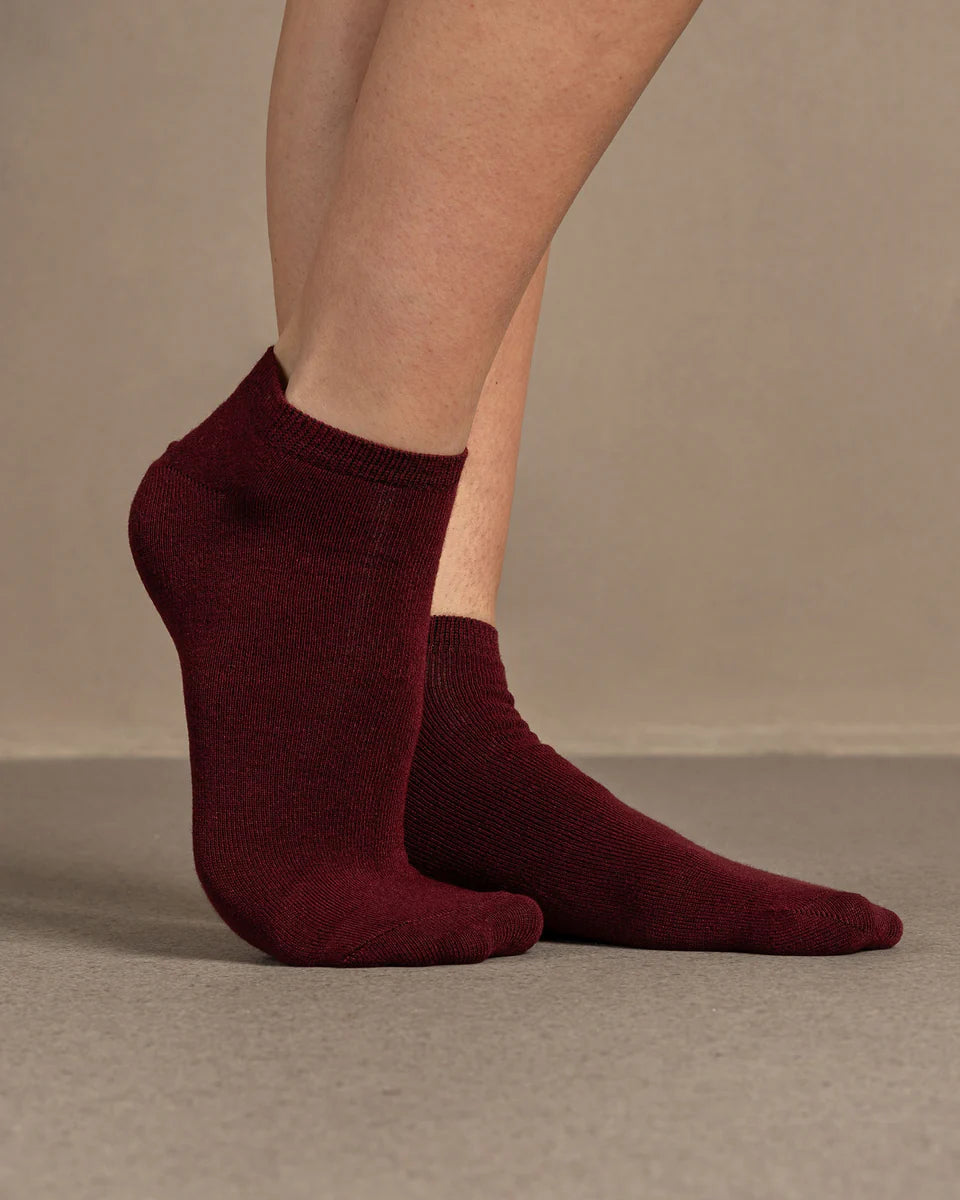Maroon socks worn by a person on a beige background