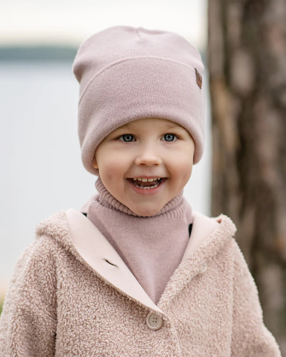 Child wearing a dusty pink knitted merino-cashmere beanie outdoors