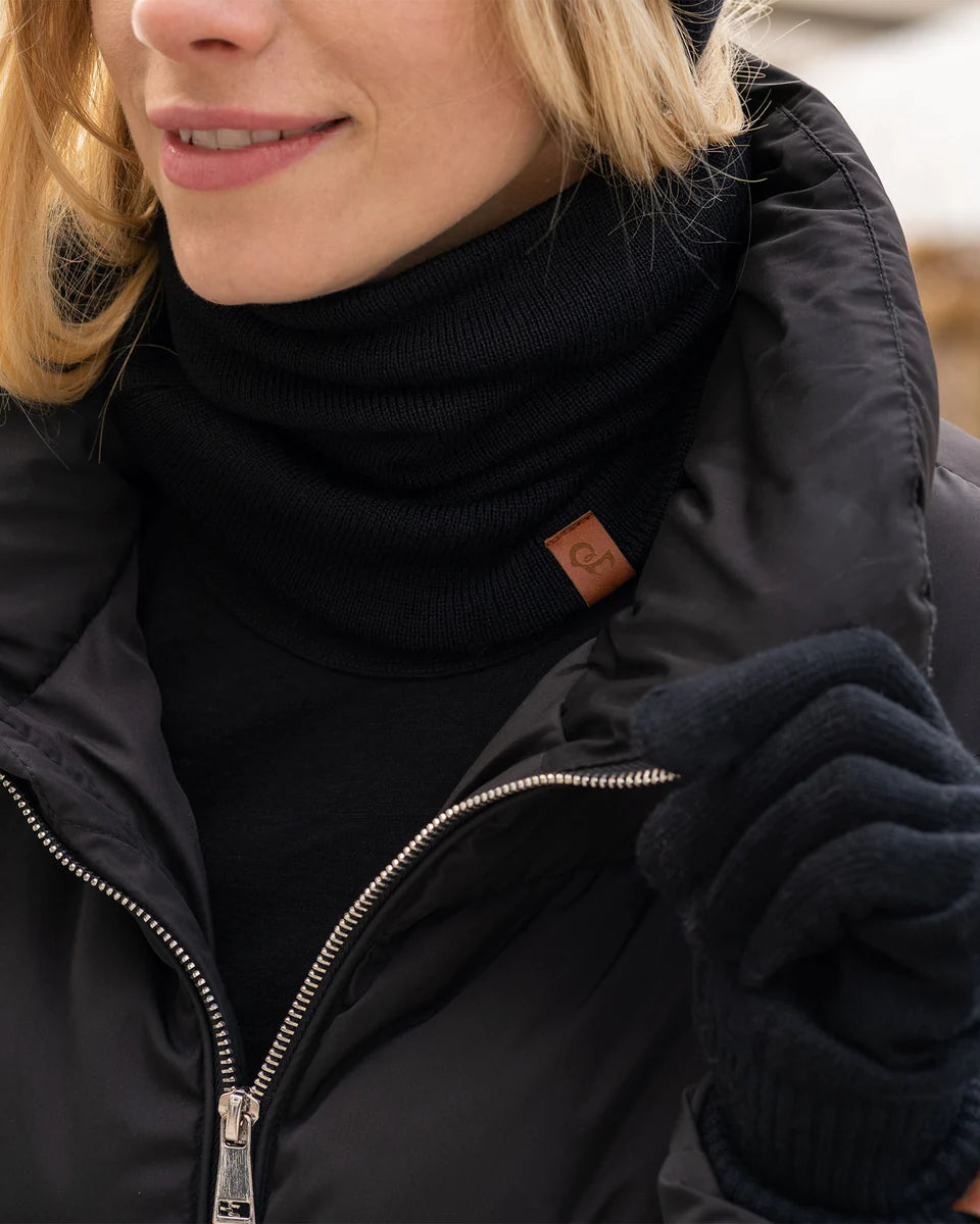 Person wearing a black jacket with a brand logo, black turtleneck, and dark gloves.