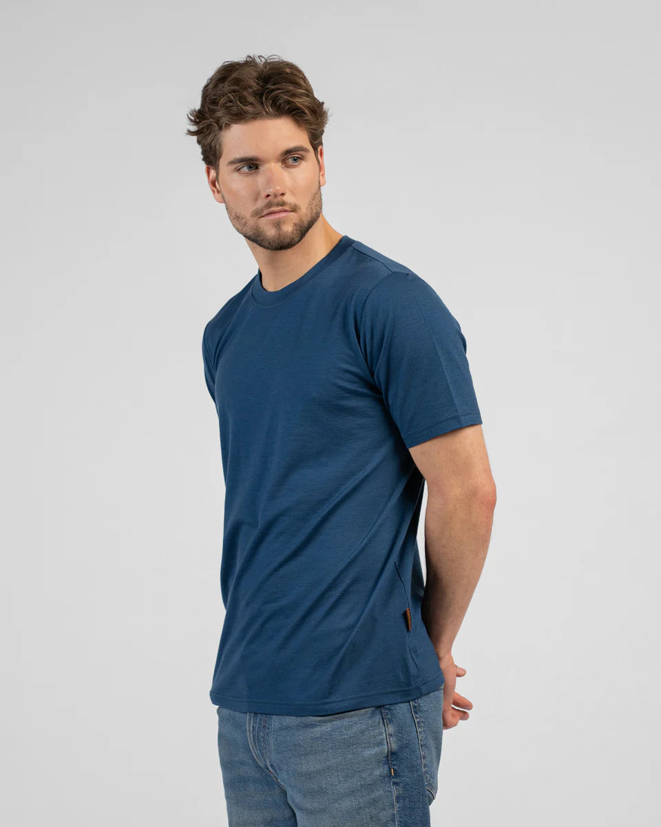 Man wearing a blue t-shirt and jeans on a gray background