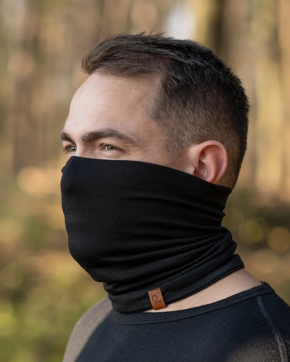 Man wearing a black neck gaiter with a blurred forest background