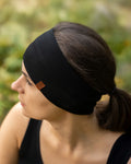 Woman wearing a black headband with a brand logo outdoors