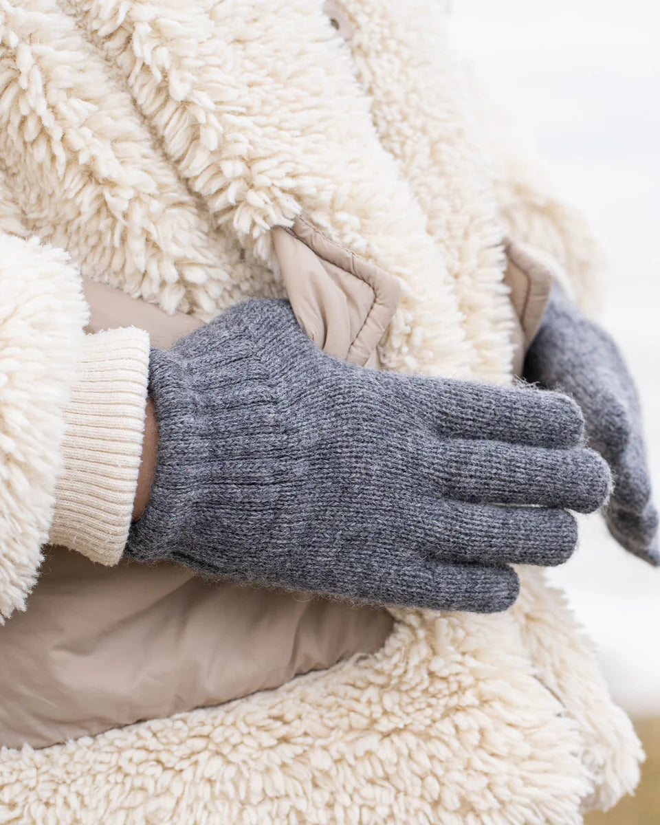 Gray gloves being worn on a white background