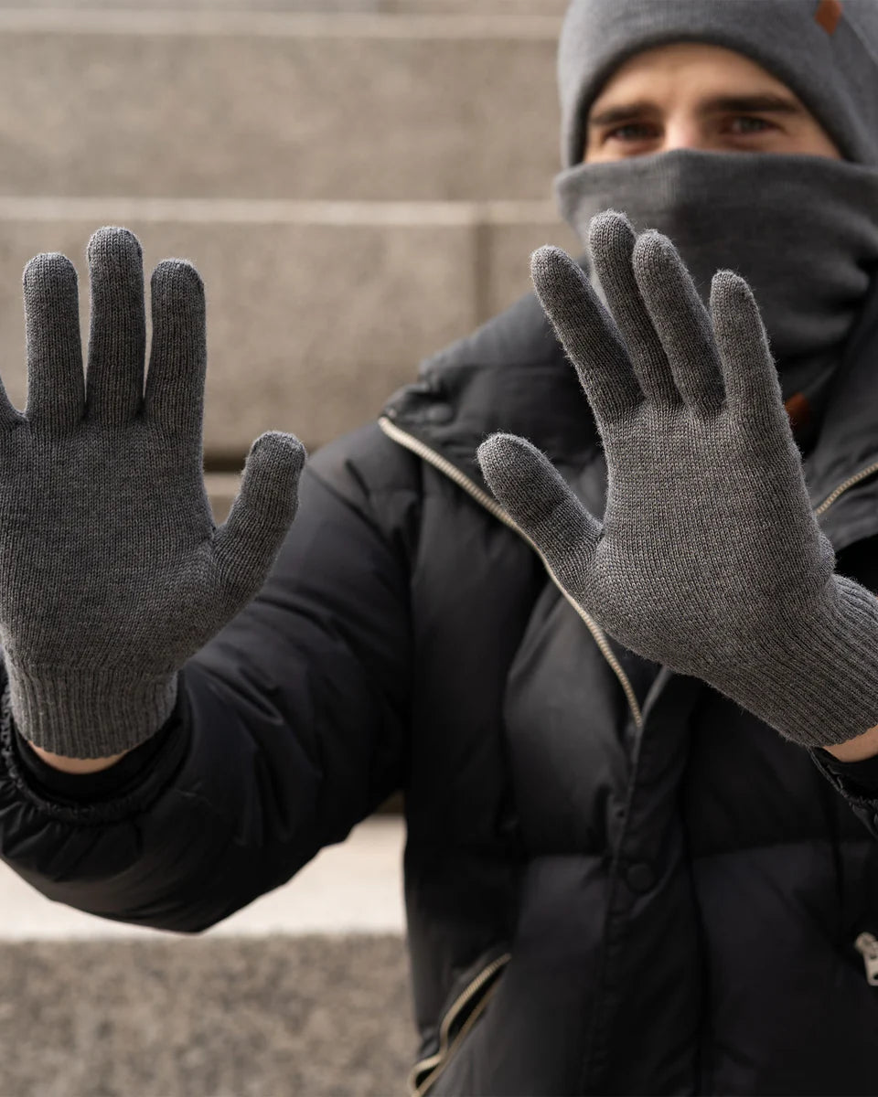Person wearing dark gray gloves and a dark jacket with a blurred background