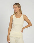 Woman wearing a natural tank top and pants against a plain background