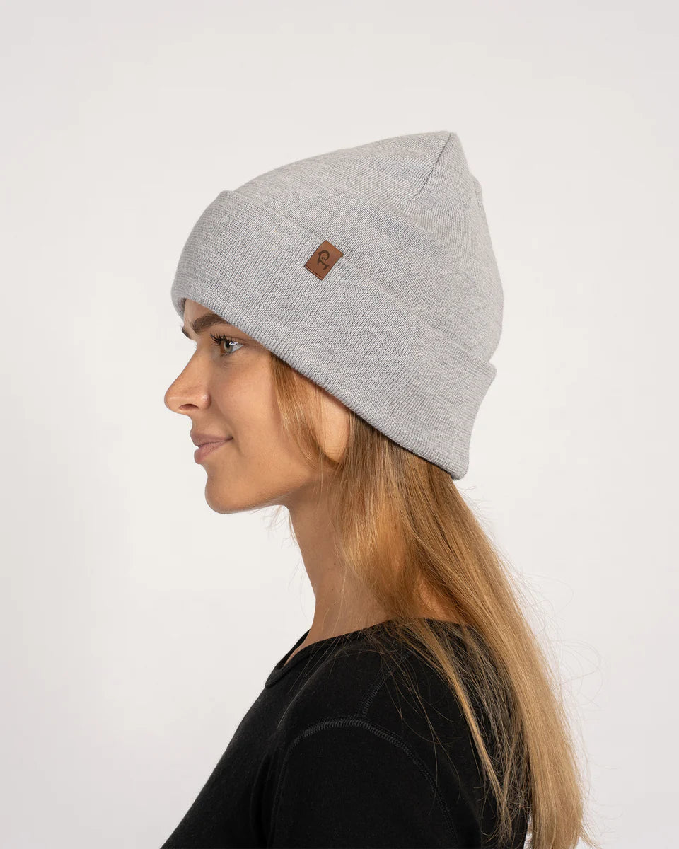 Woman wearing a gray beanie with a brand logo on a white background
