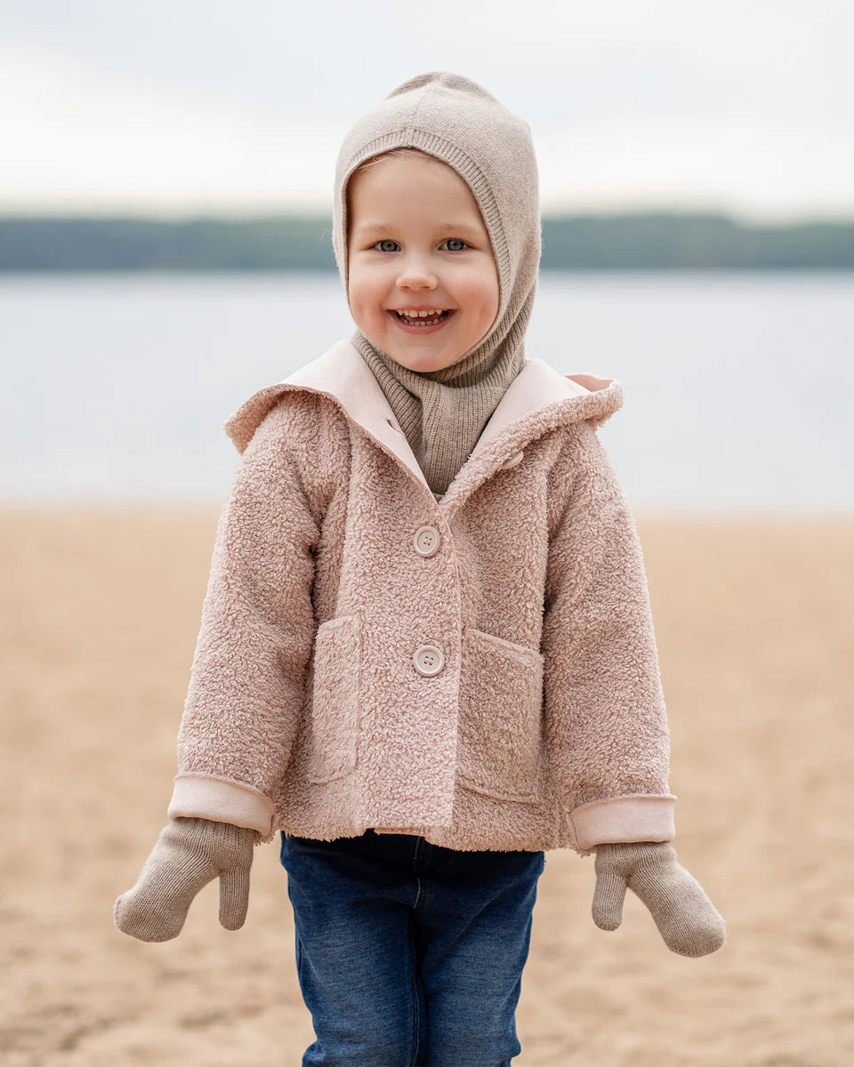 Child wearing a creamy beige knitted merino hooded balaclava outdoors