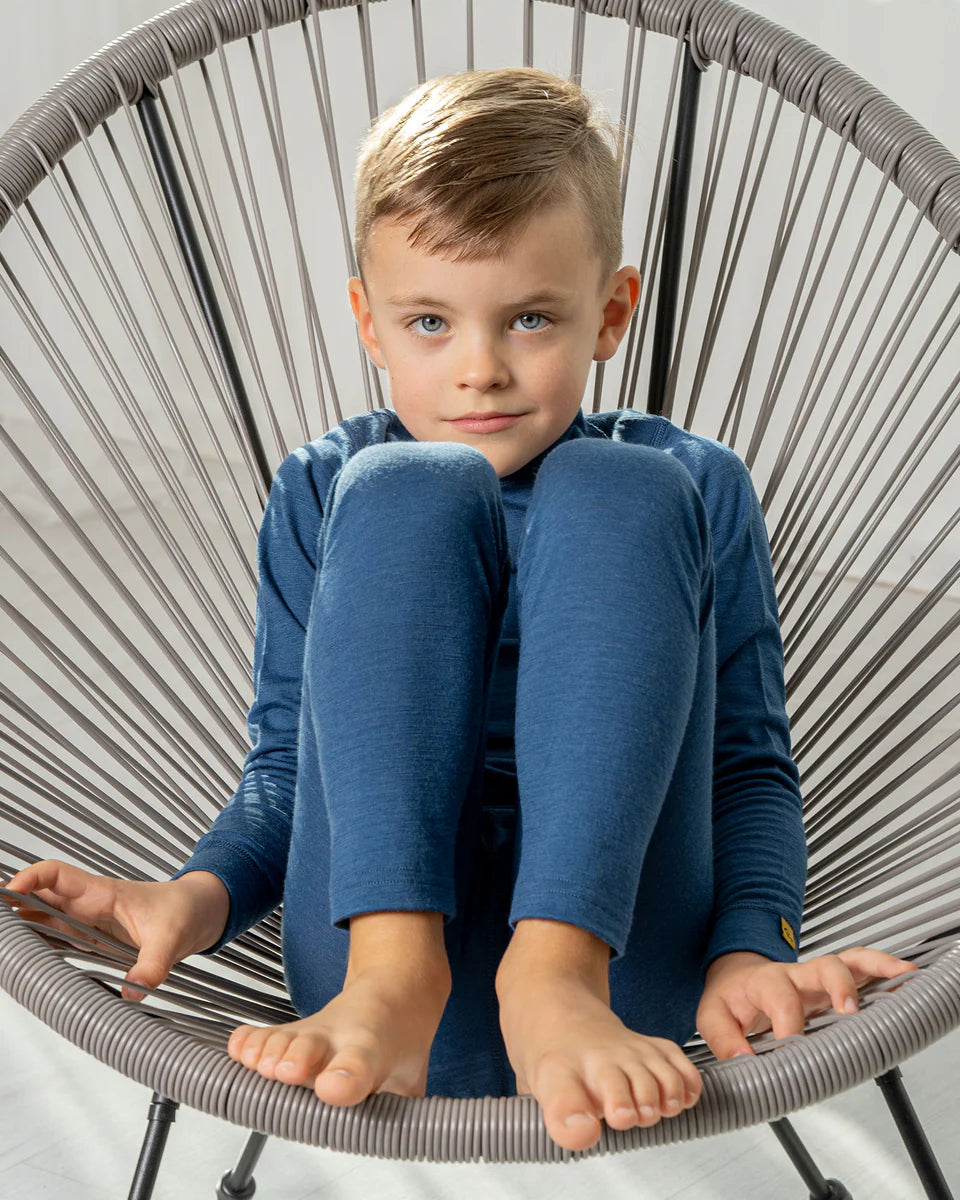 Young boy sitting on a modern chair wearing a blue outfit.