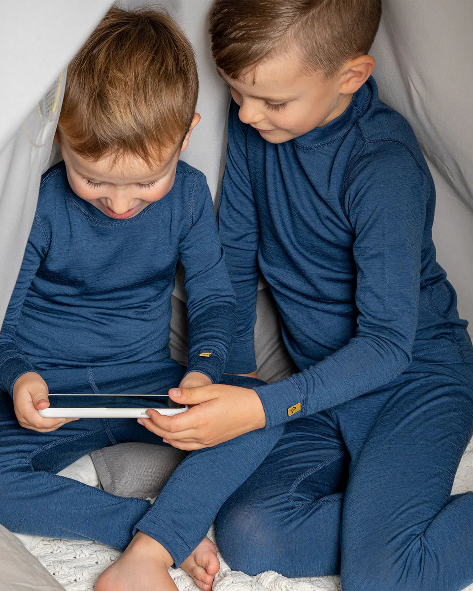 Two children in matching blue outfits sitting together, looking at a tablet.