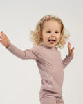Child wearing a pink long-sleeve shirt and pants on a white background