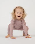 Child wearing a pink outfit on a white background