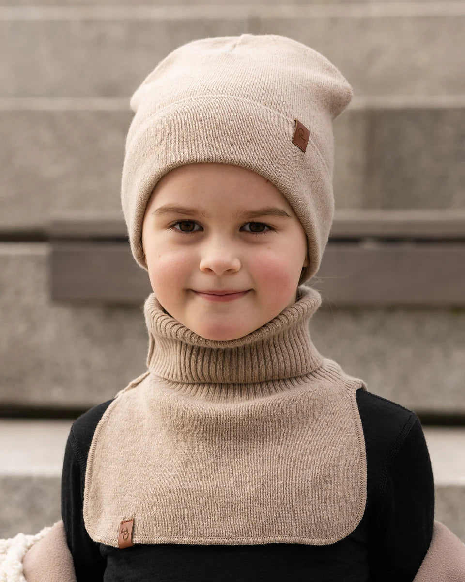 Child wearing a beige knitted merino dickie bib