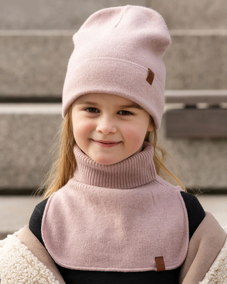 Child wearing a dusty pink knitted merino dickie bib