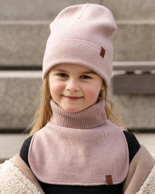 Child wearing a dusty pink knitted merino dickie bib