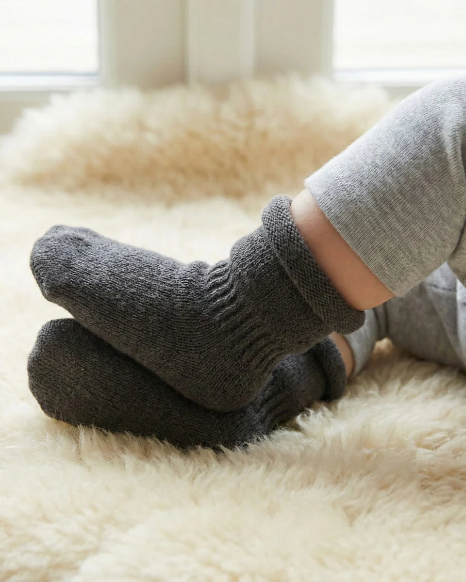 Person wearing dark gray socks on a fluffy white rug