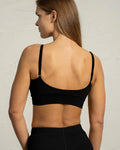 Woman wearing a black sports bra against a plain background
