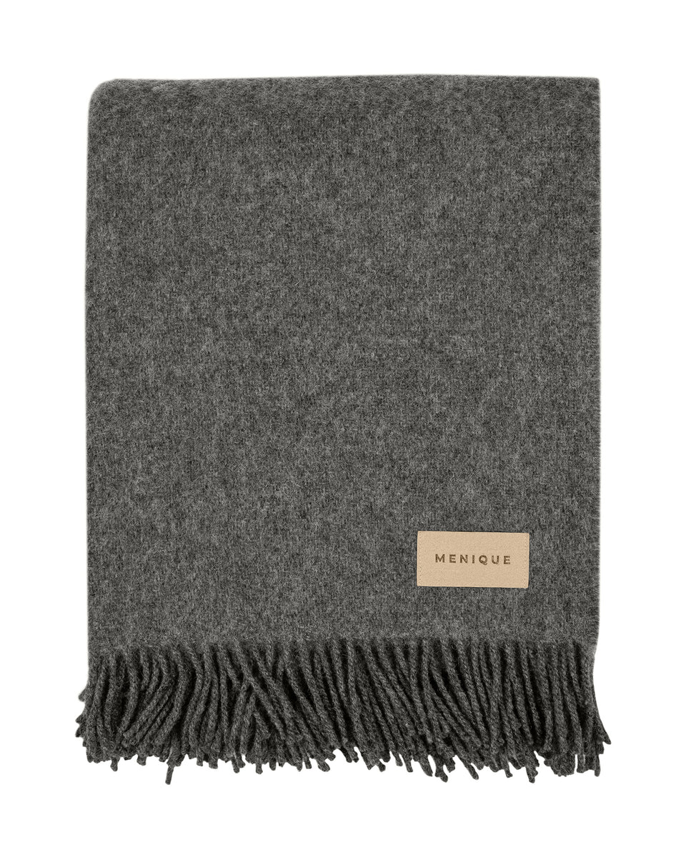 Gray blanket with fringes and a brand label on a white background